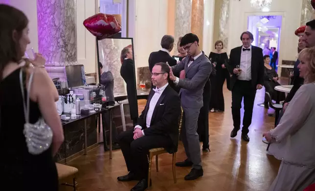A hairdresser straightens a man's hair during the opening ceremony of the Lawyers' Ball in Vienna, Austria, Saturday, March 1, 2025. (AP Photo/Denes Erdos)