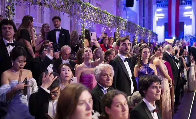 People watch and take pictures during the opening ceremony of the Lawyers' Ball in Vienna, Austria, Saturday, March 1, 2025. (AP Photo/Denes Erdos)