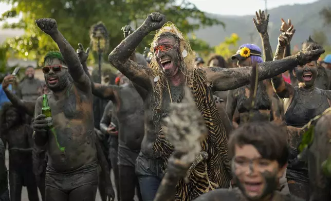 Revelers cheer during the Mud Block carnival party in Paraty, Brazil, Saturday, March 1, 2025. (AP Photo/Andre Penner)
