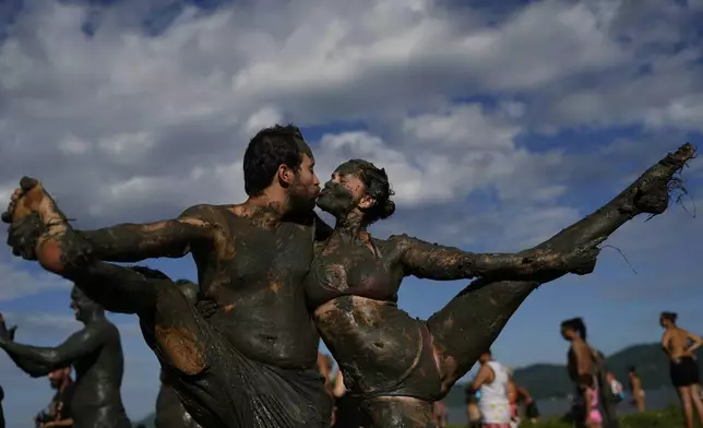 Revelers share a kiss during the traditional Mud Block carnival party in Paraty, Brazil, Saturday, March 1, 2025. (AP Photo/Andre Penner)