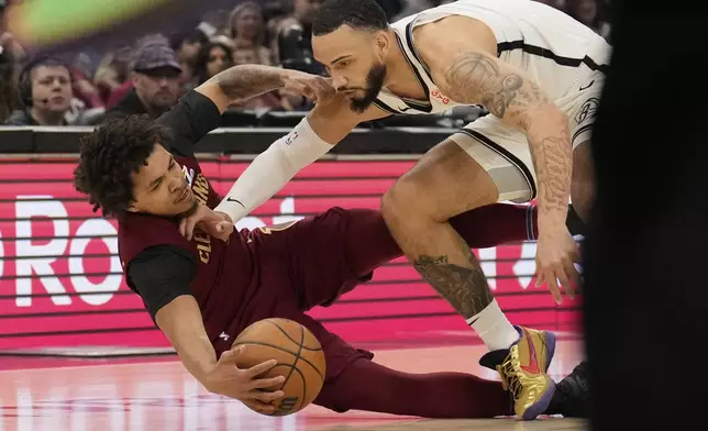 Cleveland Cavaliers guard Craig Porter Jr., left, and Brooklyn Nets forward Tyrese Martin, right, dive for the ball in the first half of an NBA basketball game Tuesday, March 11, 2025, in Cleveland. (AP Photo/Sue Ogrocki)