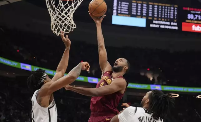 Cleveland Cavaliers forward Evan Mobley, center, shoots between Brooklyn Nets center Nic Claxton, left, and forward Ziaire Williams, right, in the first half of an NBA basketball game Tuesday, March 11, 2025, in Cleveland. (AP Photo/Sue Ogrocki)