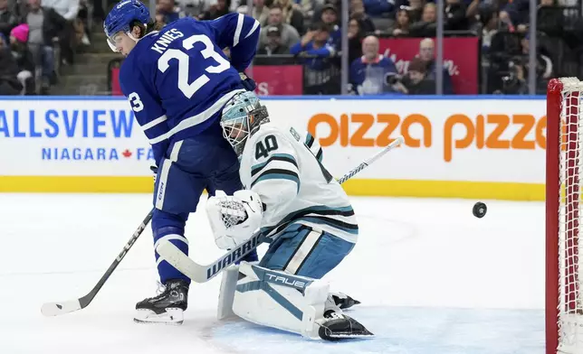 Toronto Maple Leafs forward Matthew Knies (23) screens San Jose Sharks goaltender Alexandar Georgiev (40) as the puck sails into the net during second-period NHL hockey game action in Toronto, Monday, March 3, 2025. (Nathan Denette/The Canadian Press via AP