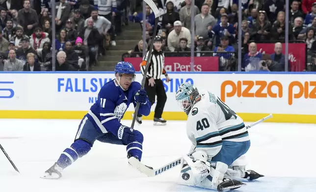 San Jose Sharks goaltender Alexandar Georgiev (40) makes a save against Toronto Maple Leafs forward Max Domi (11) during second-period NHL hockey game action in Toronto, Monday, March 3, 2025. (Nathan Denette/The Canadian Press via AP