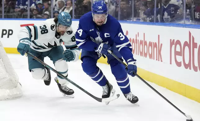 Toronto Maple Leafs forward Auston Matthews (34) moves the puck around the net under pressure from San Jose Sharks defenceman Mario Ferraro (38) during the second period of an NHL hockey game in Toronto, Monday, March 3, 2025. (Nathan Denette/The Canadian Press via AP)