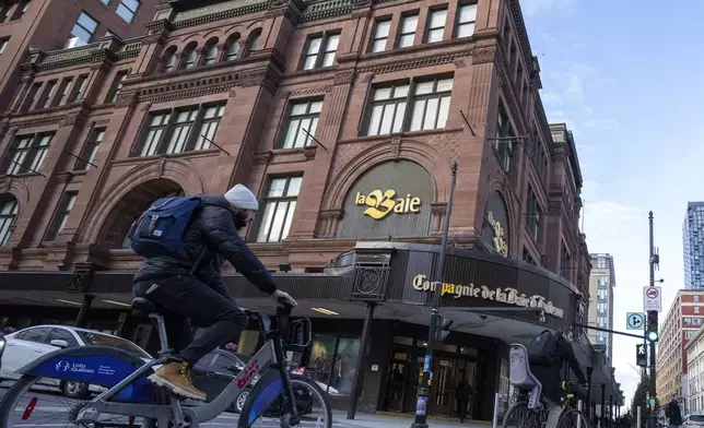 People cycle past the Hudson's Bay department store in downtown Montreal, Monday, March 17, 2025. (Christinne Muschi/The Canadian Press via AP)