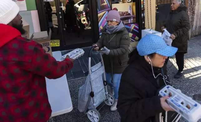 Abou Sow hands out cartons of eggs to people waiting in line to receive free eggs from FarmerJawn Agriculture, Friday, March 21, 2025, in the Harlem neighborhood of New York. (AP Photo/Julia Demaree Nikhinson)