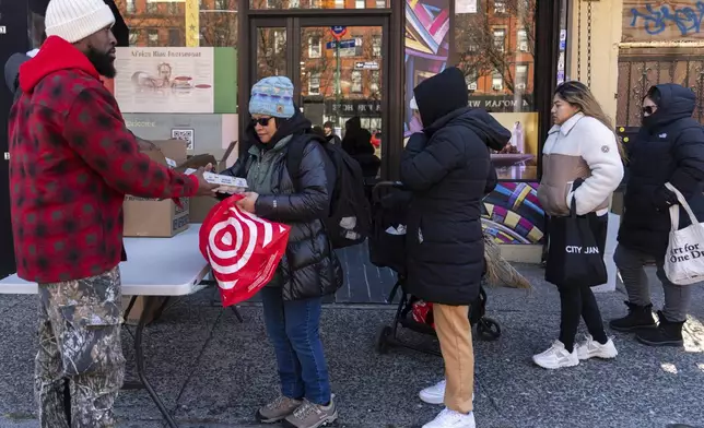 Abou Sow hands out cartons of eggs to people waiting in line to receive free eggs from FarmerJawn Agriculture, Friday, March 21, 2025, in the Harlem neighborhood of New York. (AP Photo/Julia Demaree Nikhinson)