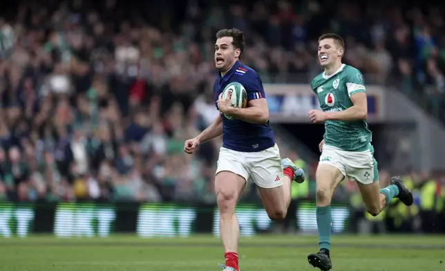 France's Damian Penaud, left, breaks away from Ireland's Sam Prendergast, to score a try during the Six Nations rugby union match between Ireland and France, at Aviva Stadium, Dublin, Ireland, Saturday, March 8, 2025. (AP Photo/Peter Morrison)