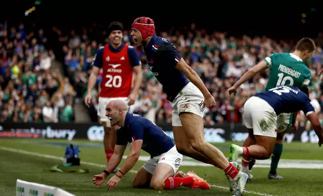France's Louis Bielle-Biarrey, centre, celebrates with his teammate Maxime Lucu, after scoring a try during the Six Nations rugby union match between Ireland and France, at Aviva Stadium, Dublin, Ireland, Saturday, March 8, 2025. (AP Photo/Peter Morrison)