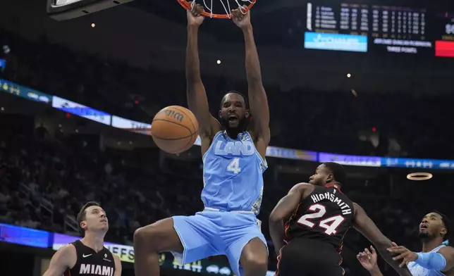 Cleveland Cavaliers forward Evan Mobley (4) dunks between Miami Heat forward Duncan Robinson (55) and forward Haywood Highsmith (24) in the first half of an NBA basketball game Wednesday, March 5, 2025, in Cleveland. (AP Photo/Sue Ogrocki)