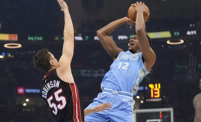 Cleveland Cavaliers forward De'Andre Hunter (12) shoots as Miami Heat forward Duncan Robinson (55) defends in the first half of an NBA basketball game Wednesday, March 5, 2025, in Cleveland. (AP Photo/Sue Ogrocki)