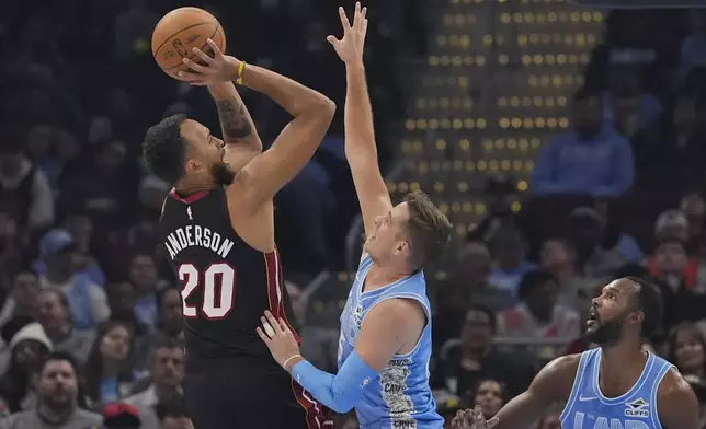 Miami Heat forward Kyle Anderson (20) shoots as Cleveland Cavaliers guard Sam Merrill, center, defends in the first half of an NBA basketball game Wednesday, March 5, 2025, in Cleveland. (AP Photo/Sue Ogrocki)