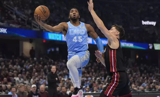 Cleveland Cavaliers guard Donovan Mitchell (45) goes to the basket past Miami Heat guard Pelle Larsson, right, in the first half of an NBA basketball game Wednesday, March 5, 2025, in Cleveland. (AP Photo/Sue Ogrocki)