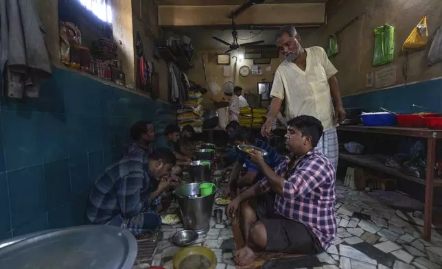 Workers from a power loom workshop eat at a local roadside eatery during lunch break, in Bhiwandi, India, Feb. 27, 2025. (AP Photo/Rafiq Maqbool)
