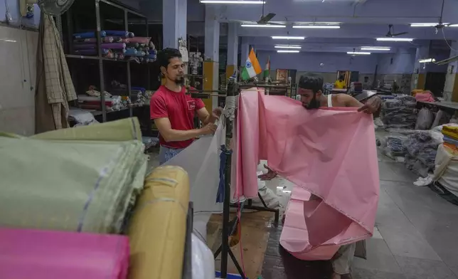 Workers measure cloth at a power weaving loom workshop in Bhiwandi, India, Feb. 27, 2025. (AP Photo/Rafiq Maqbool)