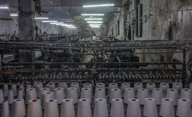Reels of yarn feed a power weaving loom at a workshop in Bhiwandi, India, Feb. 25, 2025. (AP Photo/Rafiq Maqbool)