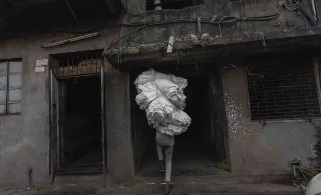 A man carries bundles of cloth manufactured at a power loom workshop in Bhiwandi, India, Feb. 27, 2025. (AP Photo/Rafiq Maqbool)