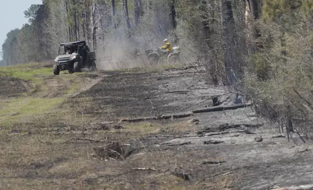 Fire crew members drive along a fire line while working to contain the Pauline Road wildfire Thursday, March 20, 2025, in Cleveland, Texas. (AP Photo/David J. Phillip)
