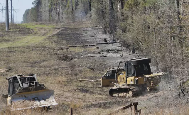 Fire crews drive along a fire line while working to contain the Pauline Road wildfire Thursday, March 20, 2025, in Cleveland, Texas. (AP Photo/David J. Phillip)