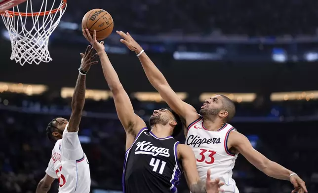 Sacramento Kings forward Trey Lyles, center, shoots as Los Angeles Clippers forward Derrick Jones Jr., left, and forward Nicolas Batum defend during the first half of an NBA basketball game Sunday, March 9, 2025, in Inglewood, Calif. (AP Photo/Mark J. Terrill)