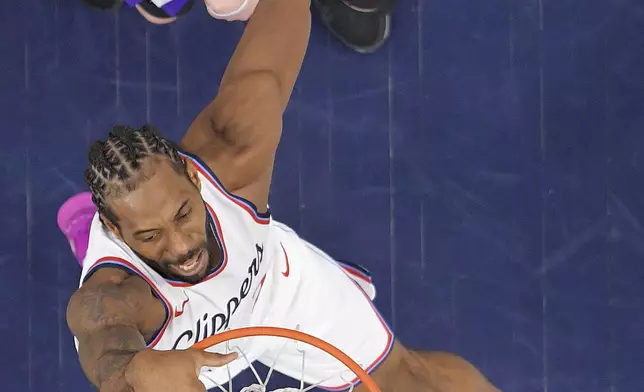 Los Angeles Clippers forward Kawhi Leonard, below, dunks as Sacramento Kings forward Jake LaRavia defends during the first half of an NBA basketball game Sunday, March 9, 2025, in Inglewood, Calif. (AP Photo/Mark J. Terrill)