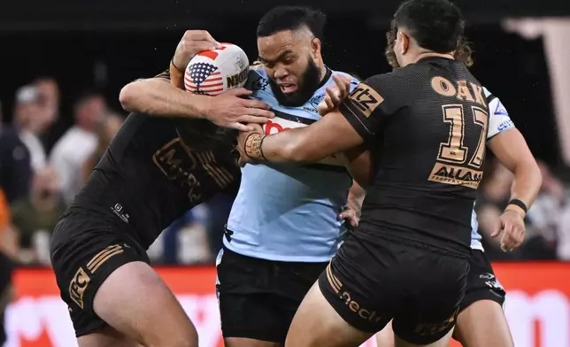 Cronulla Sharks Siosifa Talakai is tackled by defenders during Australia's National Rugby League game between the Penrith Panthers and Cronulla Sutherland-Sharks at Allegiant Stadium in Las Vegas, Saturday, March 1, 2025. (AP Photo/David Becker)