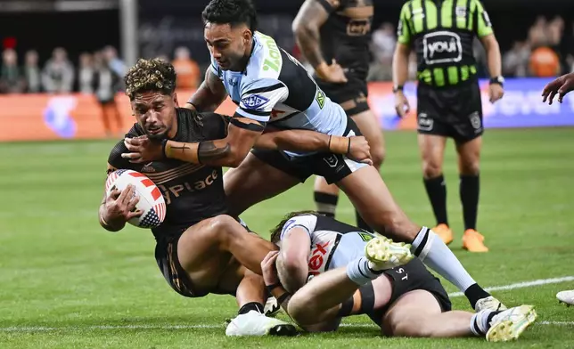 Penrith Panthers Izack Tago, left, is tackled by defenders during Australia's National Rugby League game between the Penrith Panthers and Cronulla Sutherland-Sharks at Allegiant Stadium in Las Vegas, Saturday, March 1, 2025. (AP Photo/David Becker)