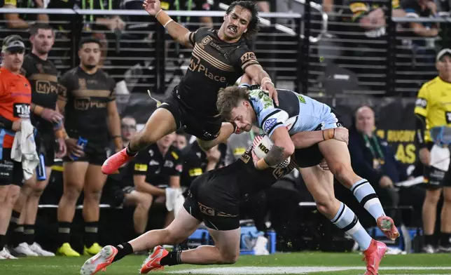 Cronulla Sharks Samuel Stonestreet, right, is tackled by defenders during Australia's National Rugby League game between the Penrith Panthers and Cronulla Sutherland-Sharks at Allegiant Stadium in Las Vegas, Saturday, March 1, 2025. (AP Photo/David Becker)