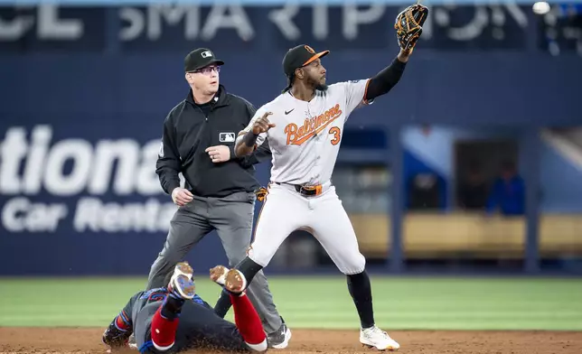 Toronto Blue Jays' Vladimir Guerrero Jr., bottom left, slides safely into second base after hitting a double as Baltimore Orioles second baseman Jorge Mateo (3) defends during third-inning baseball game action in Toronto, Friday, March 28, 2025. (Christopher Katsarov/The Canadian Press via AP)