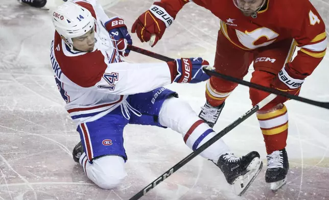 Montreal Canadiens' Nick Suzuki, left, is checked by Calgary Flames' Rasmus Andersson during first period NHL hockey action in Calgary on Saturday, March 8, 2025. (Jeff McIntosh/The Canadian Press via AP)