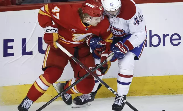 Montreal Canadiens' Alexandre Carrier, right, is checked by Calgary Flames' Connor Zary during first period NHL hockey action in Calgary on Saturday, March 8, 2025. (Jeff McIntosh/The Canadian Press via AP)
