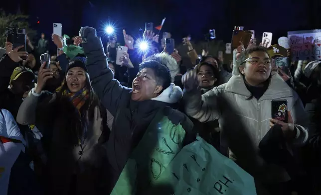 Supporters of former Philippine President Rodrigo Duterte hold up their phones and wave banners during a demonstration outside the International Criminal Court detention center near The Hague in Scheveningen, Netherlands, Wednesday, March 12, 2025. (AP Photo/Omar Havana)
