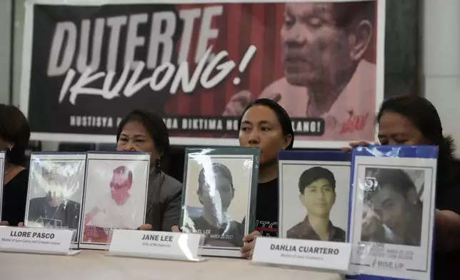 Relatives hold pictures of victims of alleged extra-judicial killings in front of a picture arrested former Philippine president Rodrigo Duterte with a sign that says "Jail Duterte" during a press conference in Quezon City, Philippines on Wednesday, March 12, 2025. (AP Photo/Aaron Favila)