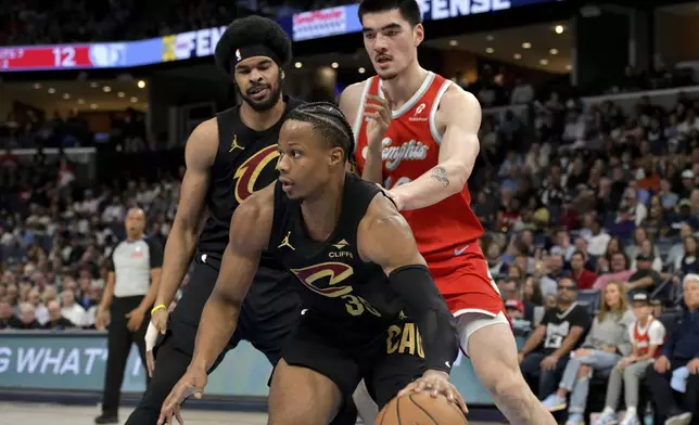 Cleveland Cavaliers forward Isaac Okoro (35) handles the ball ahead of center Jarrett Allen, left, and Memphis Grizzlies center Zach Edey (14) in the first half of an NBA basketball game Friday, March 14, 2025, in Memphis, Tenn. (AP Photo/Brandon Dill)