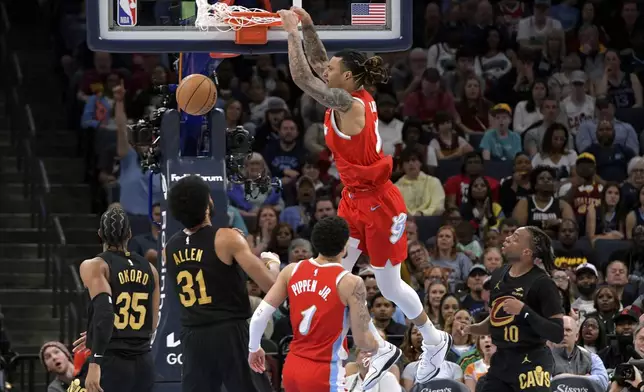 Memphis Grizzlies forward Brandon Clarke (15) dunks ahead of Cleveland Cavaliers center Jarrett Allen (31) in the first half of an NBA basketball game Friday, March 14, 2025, in Memphis, Tenn. (AP Photo/Brandon Dill)