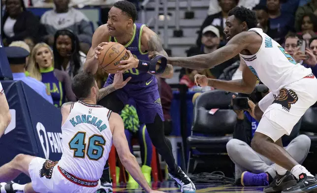 New Orleans Pelicans forward Bruce Brown (00) looses his head band against Memphis Grizzlies guards John Konchar (46) and Vince Williams Jr. (5) during the first half of an NBA basketball game in New Orleans, Sunday, March 9, 2025. (AP Photo/Matthew Hinton)