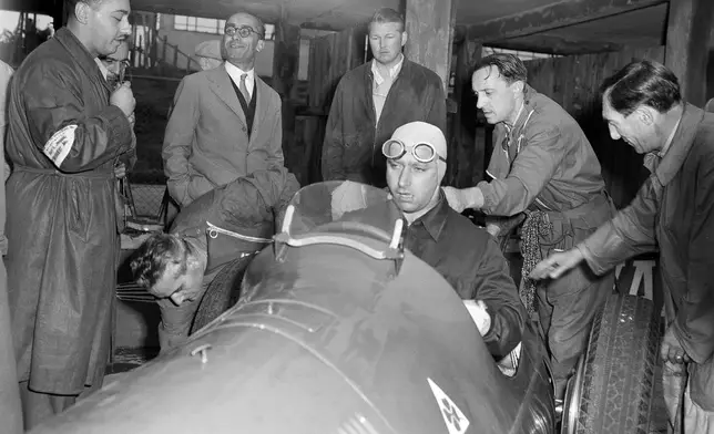 FILE - Juan Manuel Fangio sits in the cockpit of his Alfa Romeo surrounded by technicians in Frankfurt, Germany, July 27, 1951. (AP Photo/Albert Gillhausen, File)