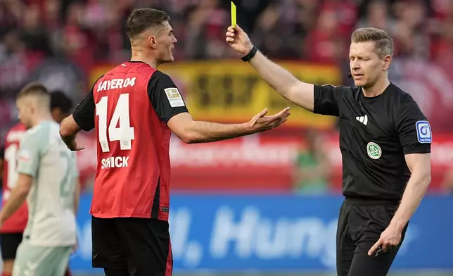 Referee Tobias Welz shows the yellow card to Leverkusen's Patrik Schick during the Bundesliga soccer match between Bayer Leverkusen and Werder Bremen at the BayArena in Leverkusen, Germany, Saturday, March 8, 2025. (AP Photo/Martin Meissner)