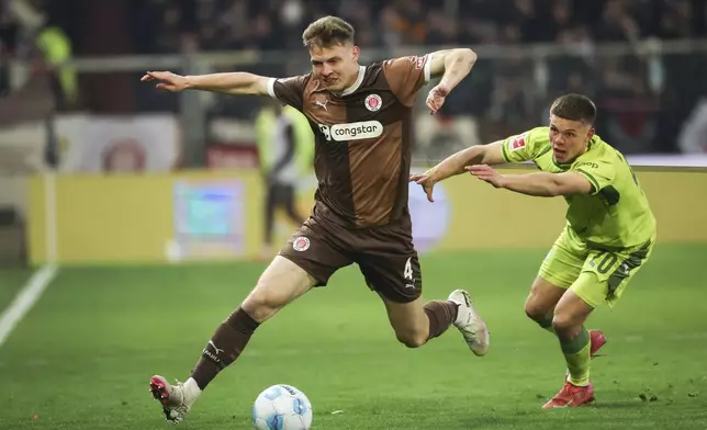St. Pauli's David Nemeth, left, and Hoffenheim's Finn Becker challenge for the ball during the Bundesliga soccer match between FC St. Pauli - TSG 1899 Hoffenheim, Millerntor Stadium, Hamburg, Germany, Friday March 14, 2025. (Christian Charisius/dpa via AP)