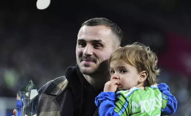 Seattle Sounders forward Jordan Morris holds his son Theo as he is honored in a halftime ceremony for becoming the club's all-time leading scorer, during an MLS soccer match against the Houston Dynamo Saturday, March 22, 2025, in Seattle. (AP Photo/Lindsey Wasson)