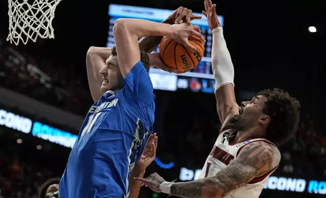 Creighton center Ryan Kalkbrenner (11) moves the basket against Louisville guard J'Vonne Hadley (1) during the first half in the first round of the NCAA college basketball tournament, Thursday, March 20, 2025, in Lexington, Ky. (AP Photo/Brynn Anderson)