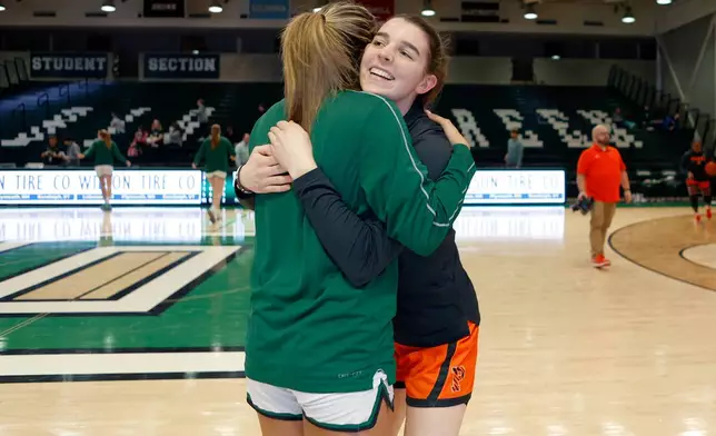 Princeton's Emily Eadie, right, Dartmouth's Annika Jiwani, two of six women from Kobe Bryant’s Mamba Academy going through their first experience with college basketball, hug before an NCAA college basketball game, Saturday, March 1, 2025, in Hanover, N.H. (AP Photo/Mary Schwalm)