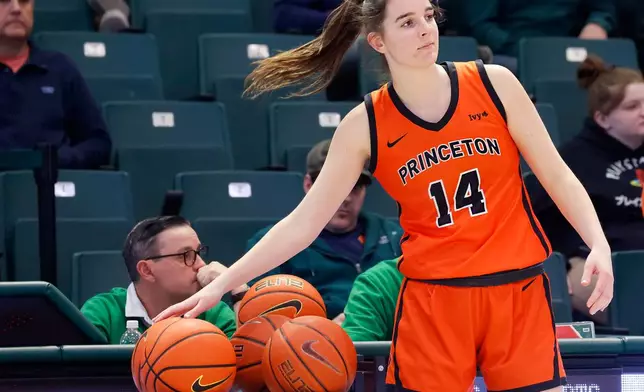 Princeton's Emily Eadie, one of six women from Kobe Bryant’s Mamba Academy going through their first experience with college basketball, places a basketball in a rack before the start of the second half of an NCAA college basketball game against Dartmouth, Saturday, March 1, 2025, in Hanover, N.H. (AP Photo/Mary Schwalm)