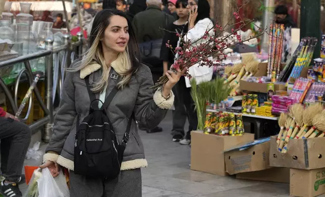 An Iranian woman carries her shopping bags including branches of a tree to decorate her New Year, or Nowruz, table at Tajrish traditional bazaar in northern Tehran, Iran, Saturday, March 15, 2025. The Persian new year, or Nowruz, which means "New Day", is the most important holiday for Iranians, it marks the beginning of the spring on vernal equinox. (AP Photo/Vahid Salemi)