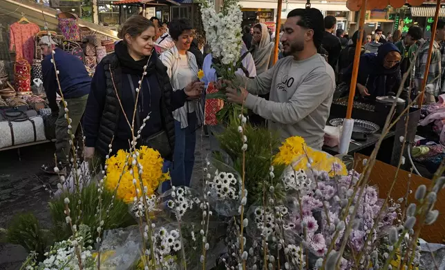 An Iranian woman buys flowers to decorate her New Year, or Nowruz, table at Tajrish traditional bazaar in northern Tehran, Iran, Saturday, March 15, 2025. The Persian new year, or Nowruz, which means "New Day", is the most important holiday for Iranians, it marks the beginning of the spring on vernal equinox. (AP Photo/Vahid Salemi)