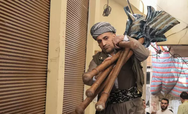 A man carries torches to be used for Nowruz, or the Persian New Year celebrations in Akra, in Iraq's northern autonomous Kurdish region, Thursday, March 20, 2025. (AP Photo/Hadi Mizban)
