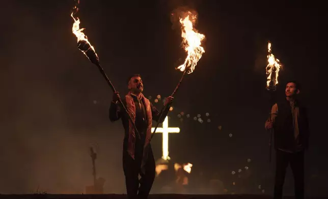 Iraqi Kurds holding lit torches walk up a mountain during a procession to celebrate their Nowruz, the Persian New Year, in Akra, Iraq, Thursday, March 20, 2025. (AP Photo/Hadi Mizban)