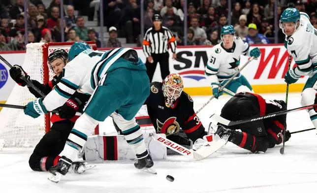 Ottawa Senators goaltender Linus Ullmark (35) watches the puck after a save as Nikolas Matinpalo (left) battles with San Jose Sharks' Klim Kostin (10) during first period NHL hockey action in Ottawa, on Saturday, March 1, 2025. (Justin Tang/The Canadian Press via AP)