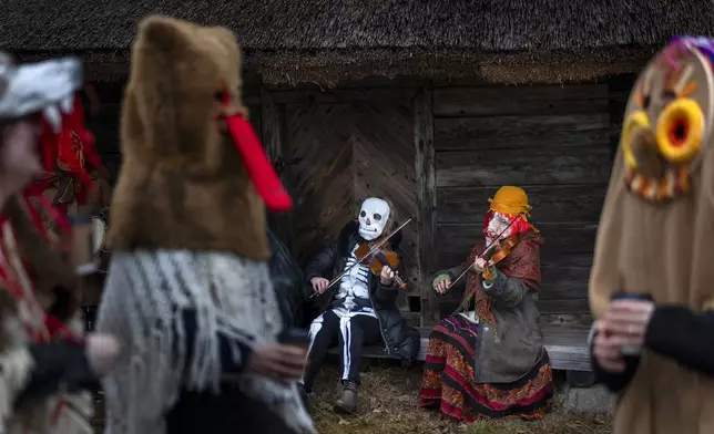 Revellers wearing traditional carnival masks take part in Shrovetide celebrations, in Rumsiskes village, some 89 kilometres (56 miles) north of Vilnius, Lithuania, Saturday, March 1, 2025. (AP Photo/Mindaugas Kulbis)
